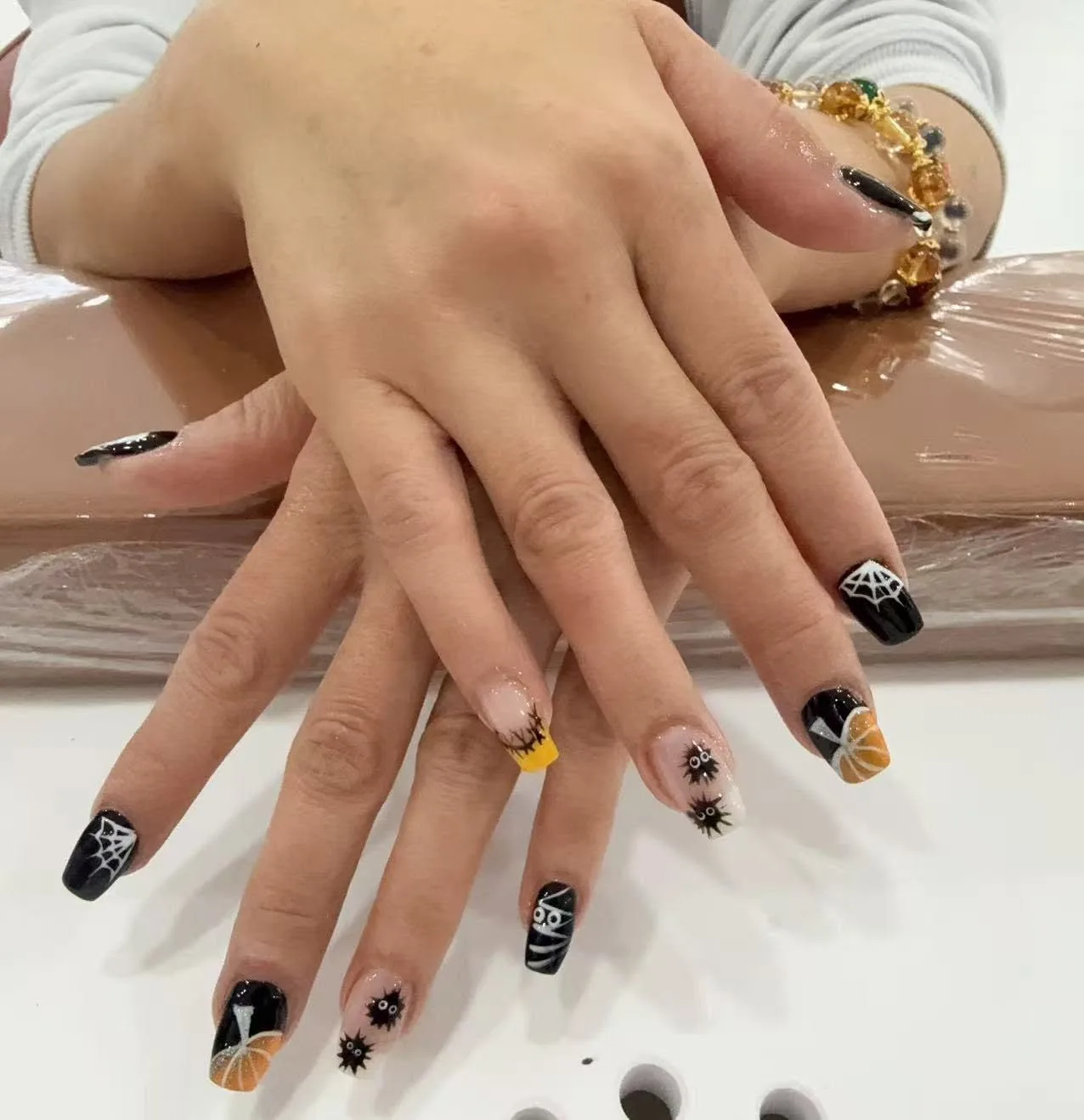 Halloween nail art: spider webs, pumpkins and a mummy on black and nude nails