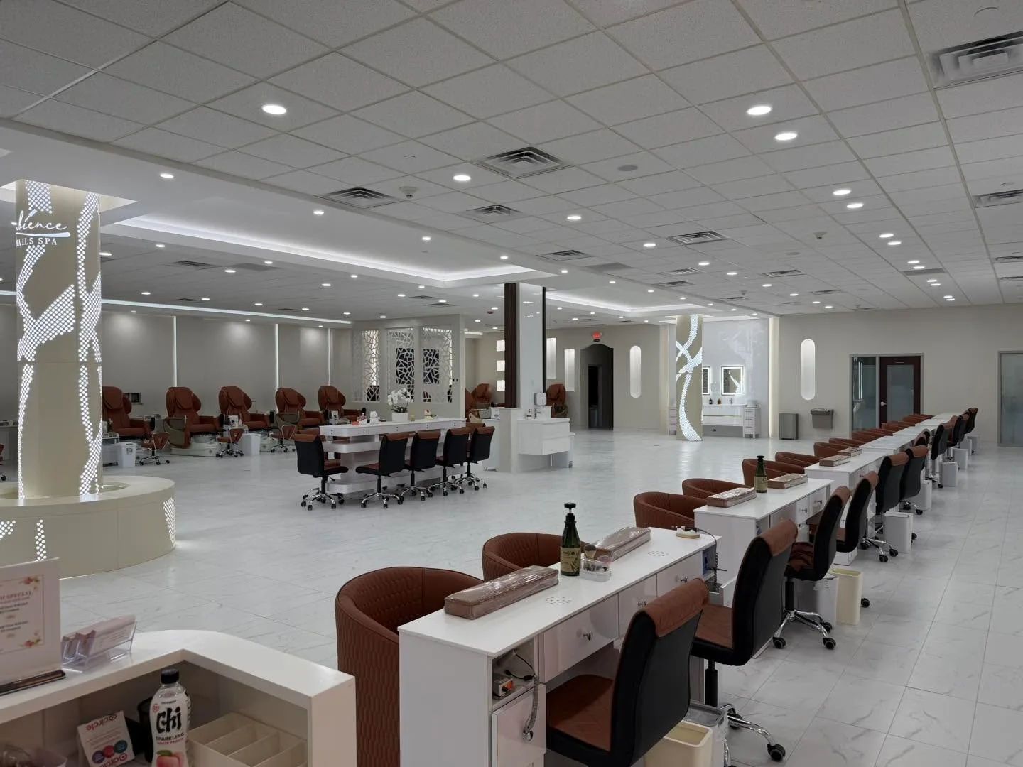 A long row of manicure tables with brown leather chairs