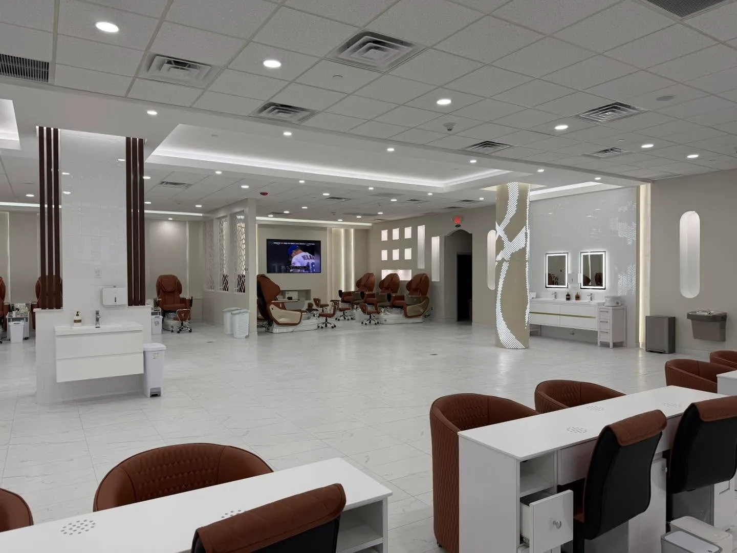 Sinks with lit mirrors, and pedicure chairs beyond