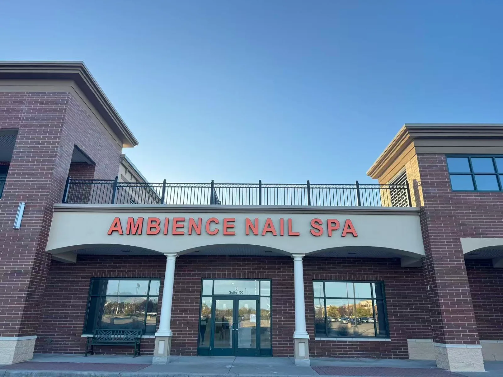 The front of the building, with AMBIENCE NAIL SPA in orange letters above the door to Suite 100